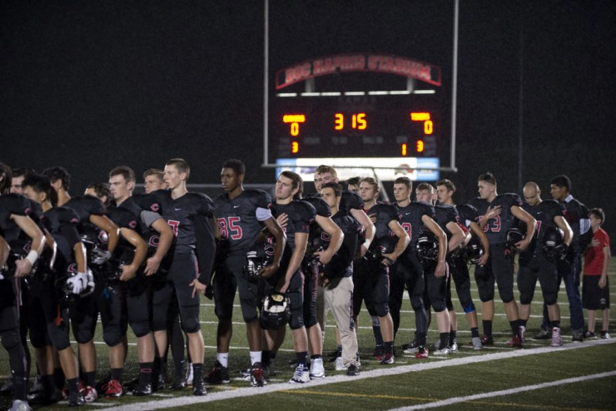 Members of the Camas High School football team remove their helmets as the National Anthem is played Friday night, Oct. 9, 2015 at Doc Harris Stadium. (Amanda Cowan/The Columbian)