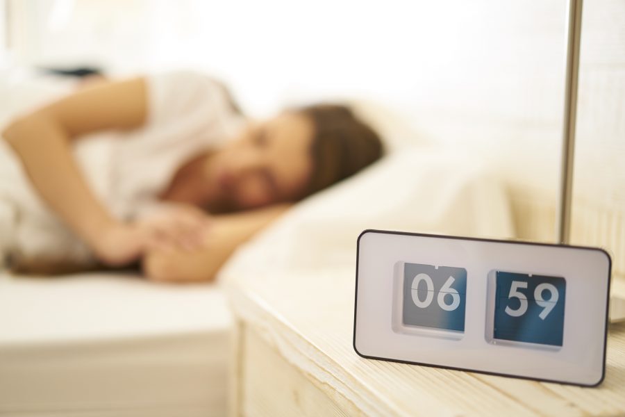 vintage flip clock with sleeping woman before wakeup call