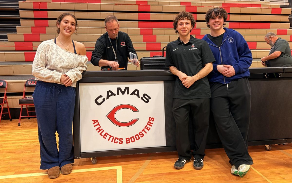 Scorekeepers Stella Mathena, Aedan Garling, and Fletcher Campbell standing in front of the CHS scorekeeping table (courtesy of Mason Marsh)